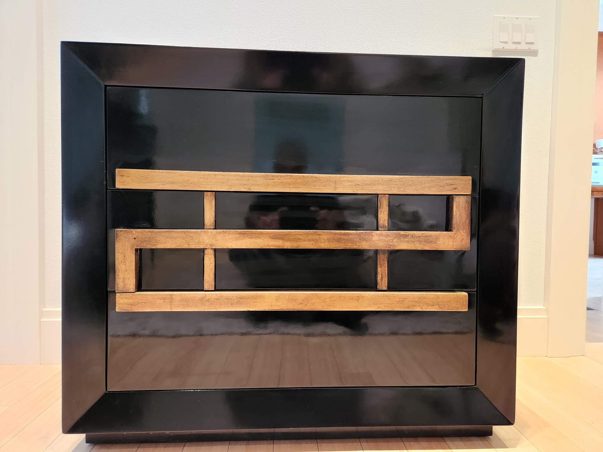 Black-lacquer chest refinished with gold geometric trim